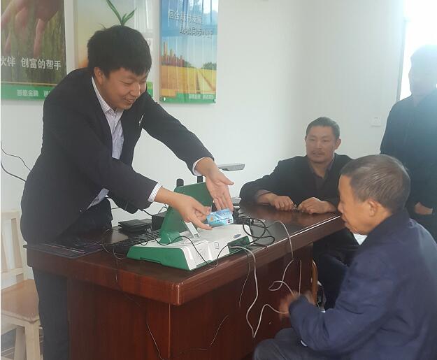 双江信用社副主任兰仕勇利用流动服务站为农户上门办理业务.jpg