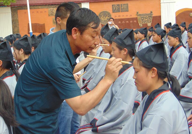 1556428171367028547.jpg 教师代表给学员点朱砂.jpg